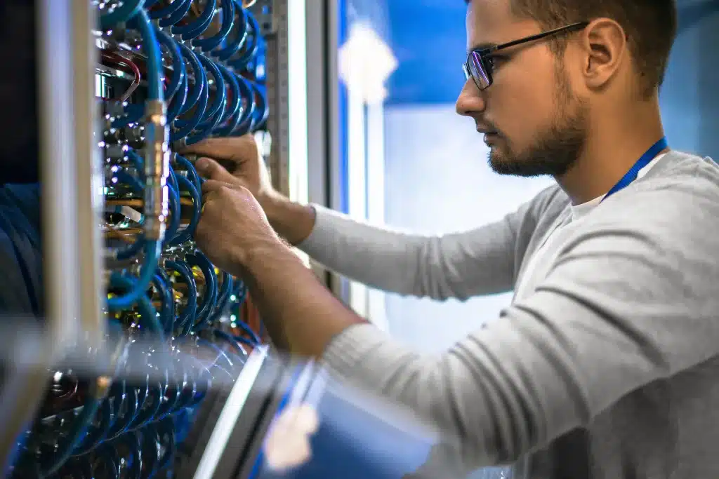 Technician connecting data cables in a server cabinet, organizing network connections in a data center environment